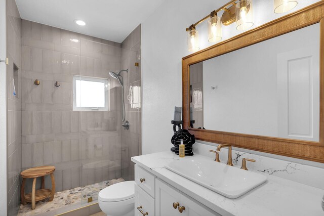 bathroom with tiled shower, vanity, and toilet