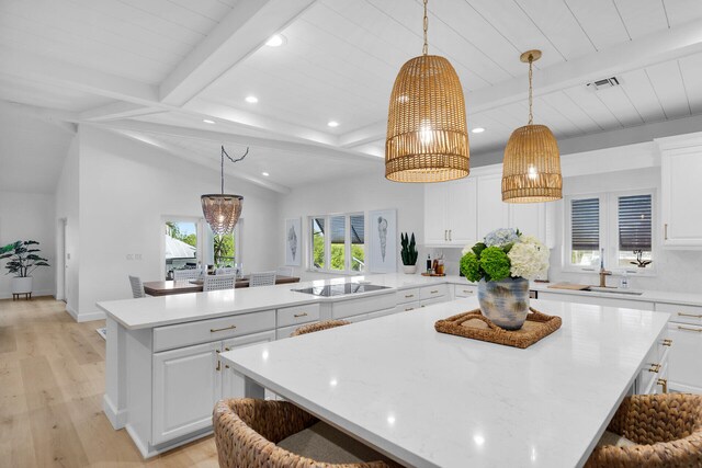 kitchen with a large island, black electric stovetop, white cabinetry, and hanging light fixtures