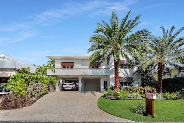 view of front of house with a balcony, a carport, and a front yard