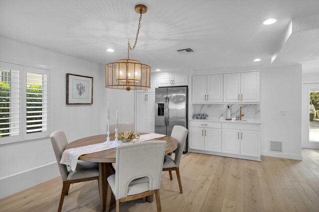 dining space with an inviting chandelier, sink, and light hardwood / wood-style flooring