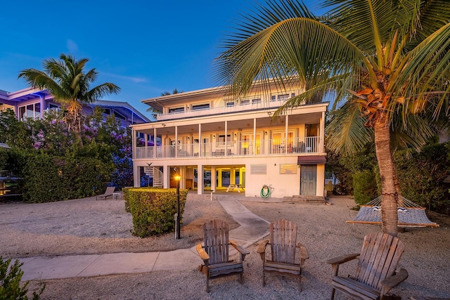 back house at dusk featuring a patio and a balcony