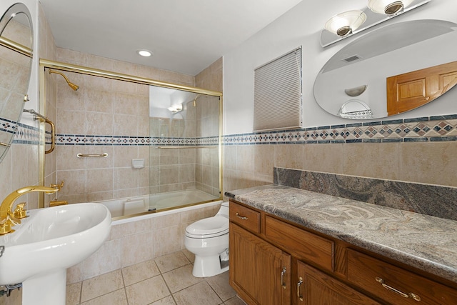 full bathroom with sink, tile walls, combined bath / shower with glass door, toilet, and tile patterned floors