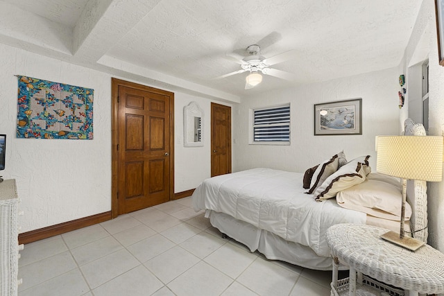 bedroom featuring a textured ceiling, a closet, light tile patterned flooring, and ceiling fan