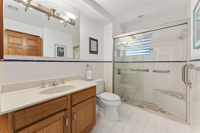 bathroom with a shower with shower door, tile patterned flooring, toilet, tile walls, and vanity