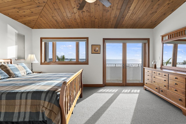 carpeted bedroom featuring multiple windows, vaulted ceiling, access to outside, and a water view