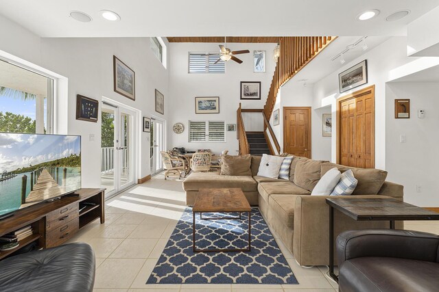 tiled living room with french doors, ceiling fan, and a towering ceiling