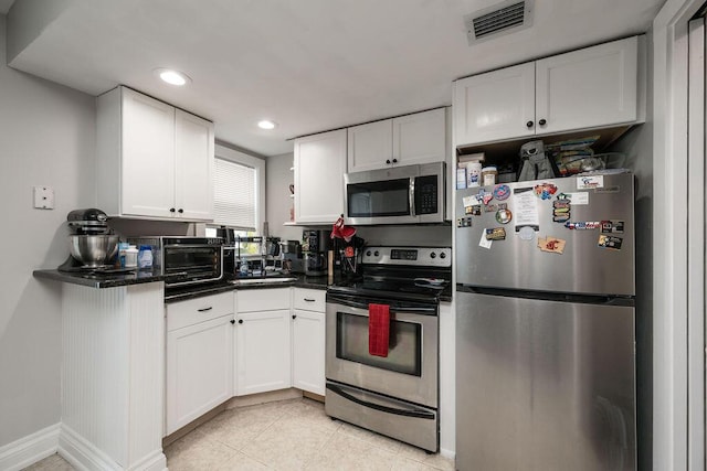 kitchen with light tile patterned floors, stainless steel appliances, and white cabinets