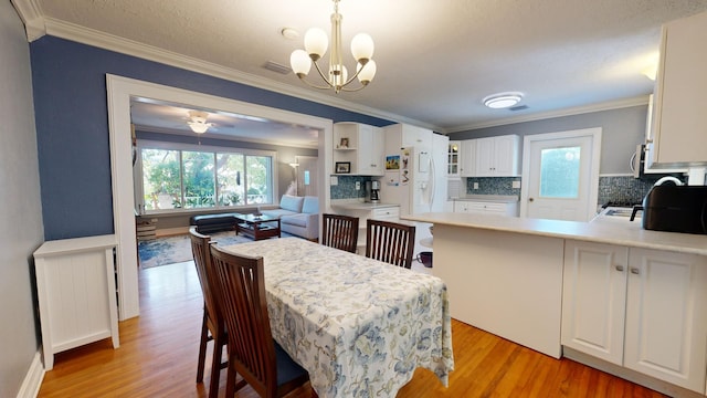 kitchen with pendant lighting, ornamental molding, a kitchen breakfast bar, and white cabinets