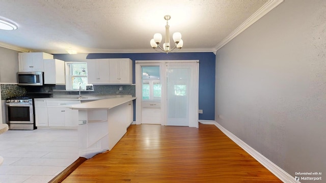 kitchen featuring white cabinetry, decorative light fixtures, stainless steel appliances, light hardwood / wood-style floors, and backsplash