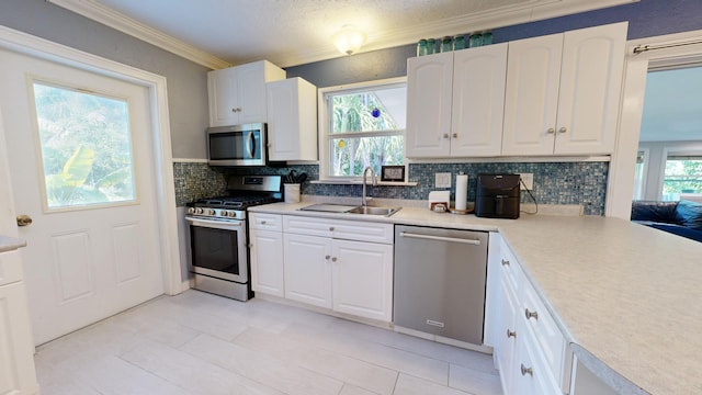 kitchen with sink, white cabinetry, ornamental molding, appliances with stainless steel finishes, and decorative backsplash