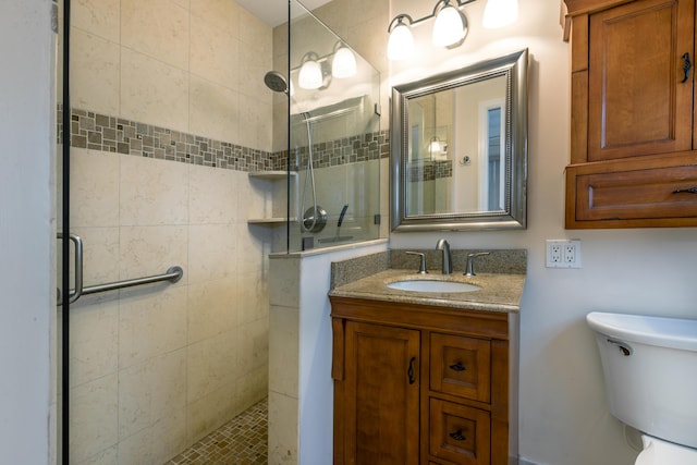 bathroom featuring a tile shower, vanity, and toilet