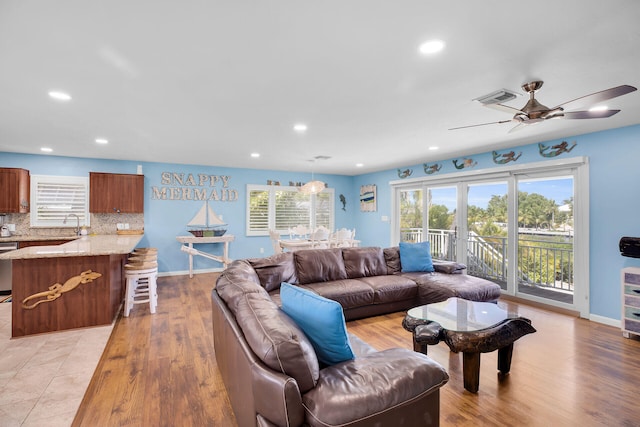 living room featuring sink, ceiling fan, and light wood-type flooring