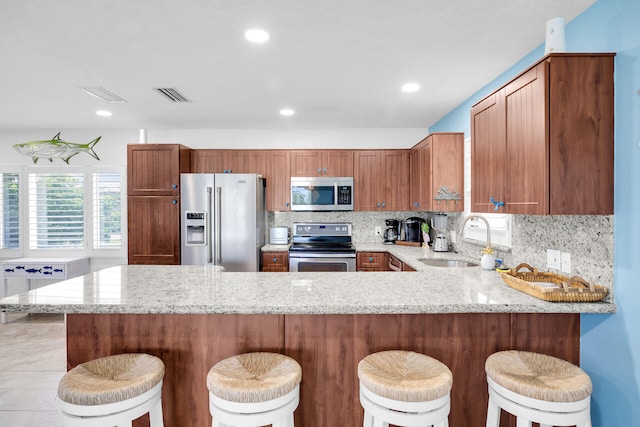 kitchen featuring sink, a breakfast bar, kitchen peninsula, and appliances with stainless steel finishes