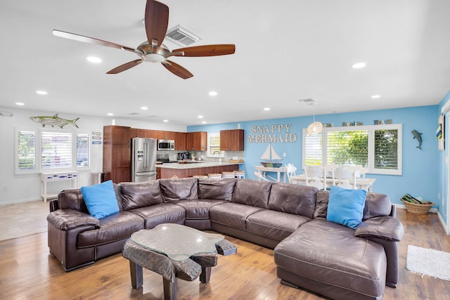 living room with sink, plenty of natural light, ceiling fan, and light wood-type flooring