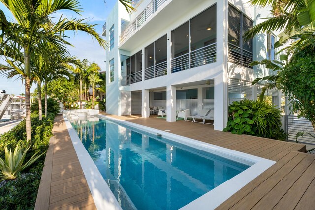 view of pool featuring a wooden deck and a sunroom