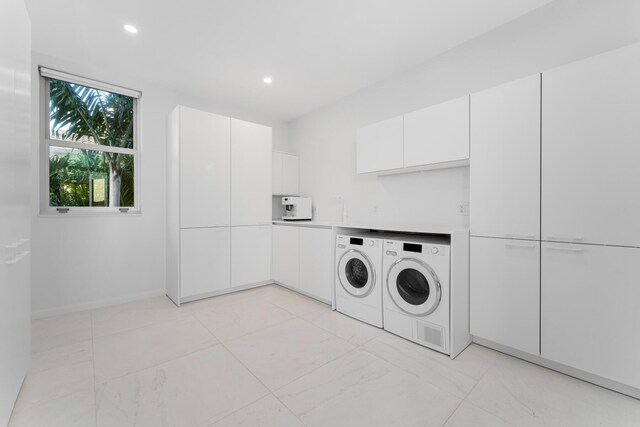 washroom with cabinets and washing machine and dryer