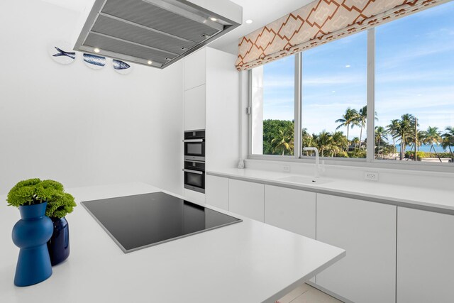 kitchen with white cabinetry, sink, black electric cooktop, and wall chimney exhaust hood