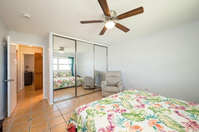 tiled bedroom with ceiling fan and a closet