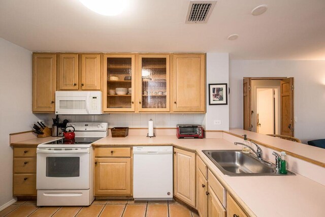 kitchen featuring light brown cabinetry, sink, and white appliances