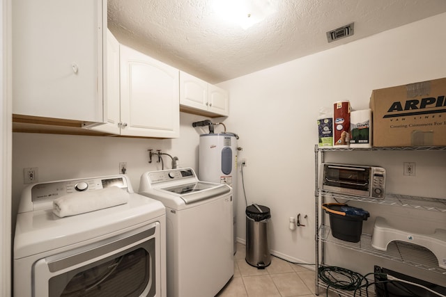 laundry area featuring light tile patterned floors, electric water heater, cabinets, a textured ceiling, and washing machine and clothes dryer