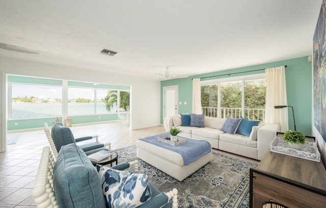 living room featuring a water view, plenty of natural light, light tile patterned floors, and ceiling fan