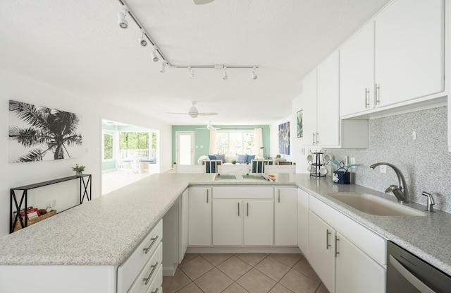 kitchen featuring white cabinetry, sink, stainless steel dishwasher, and kitchen peninsula