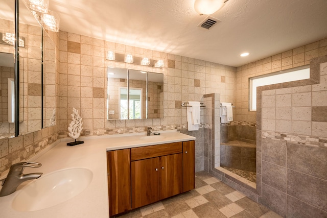 bathroom with tile walls, vanity, a textured ceiling, and tiled shower