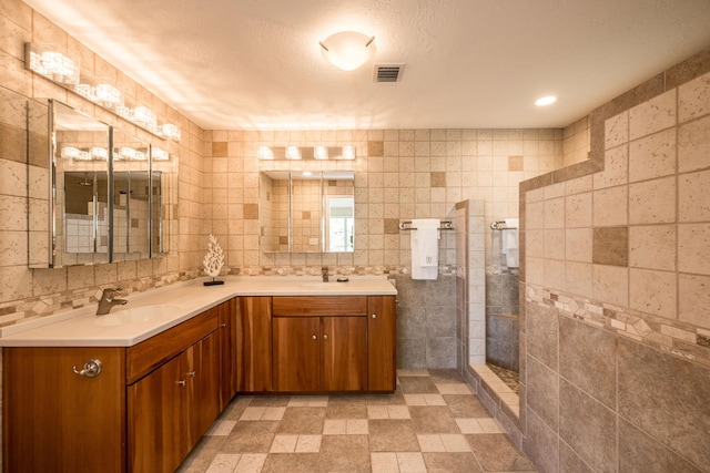 bathroom featuring tile walls, vanity, tasteful backsplash, a textured ceiling, and a shower