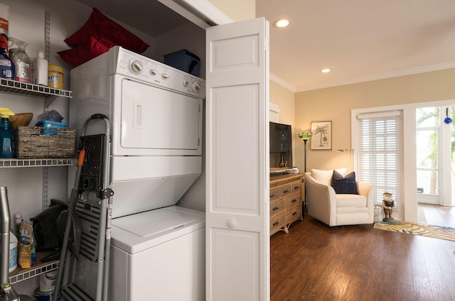 clothes washing area featuring dark hardwood / wood-style flooring, ornamental molding, and stacked washer and clothes dryer