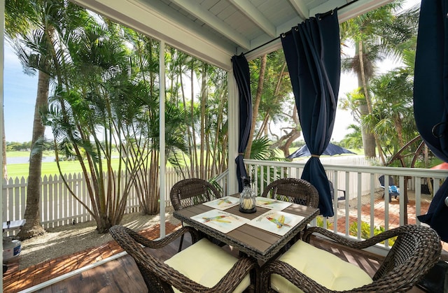 sunroom / solarium featuring beamed ceiling and plenty of natural light