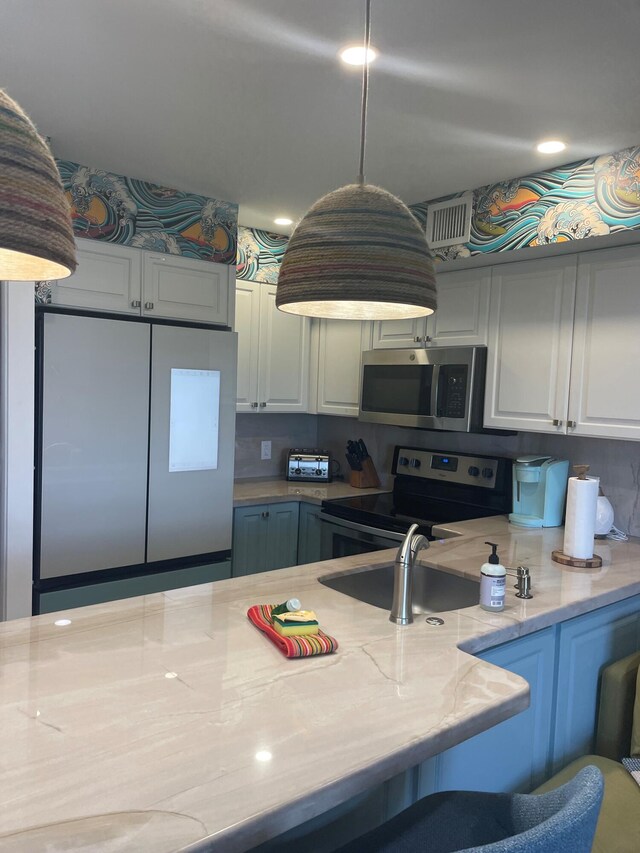 kitchen featuring white cabinets, light stone counters, stainless steel appliances, and a sink