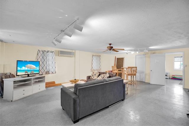 living room with rail lighting, a wall mounted air conditioner, ceiling fan, and a textured ceiling