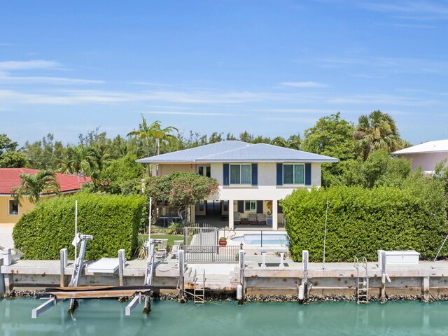 rear view of house with a water view, a pool, and a patio area