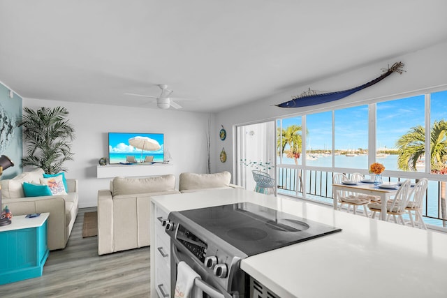 kitchen featuring ceiling fan, light hardwood / wood-style floors, stainless steel electric range, and white cabinets