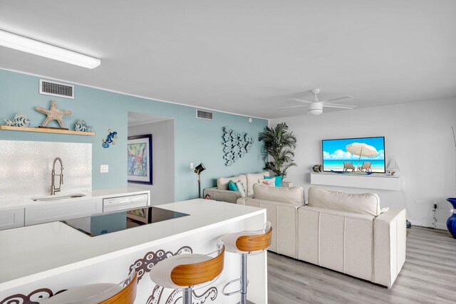 living room featuring ceiling fan, sink, and light hardwood / wood-style floors