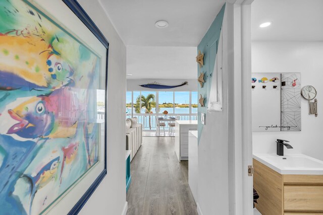 hall with wood-type flooring, a water view, and sink