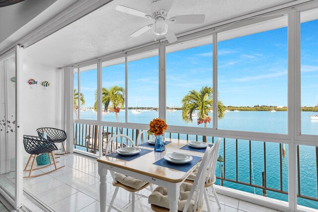 sunroom featuring a water view and ceiling fan