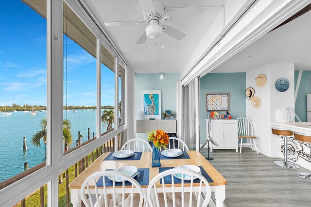 sunroom / solarium featuring a water view and ceiling fan