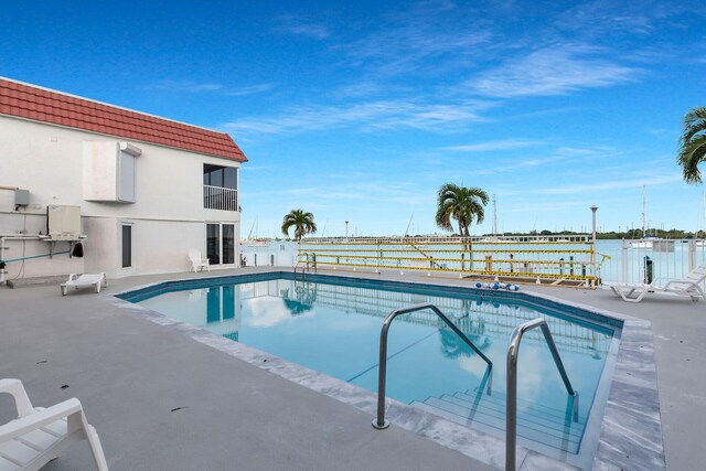 view of swimming pool featuring a water view and a patio area