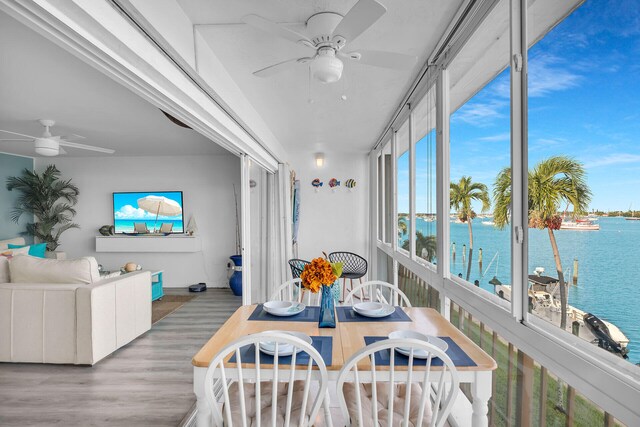 sunroom / solarium with ceiling fan and a water view