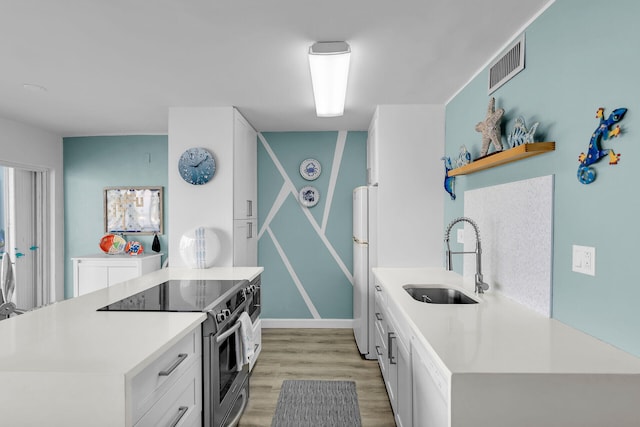 kitchen with electric stove, white cabinetry, sink, white refrigerator, and light hardwood / wood-style flooring