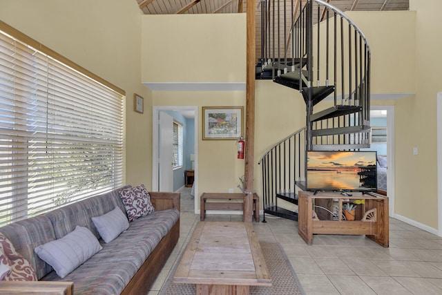 living room with tile patterned flooring, stairway, baseboards, and a high ceiling