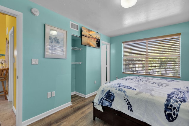 bedroom featuring visible vents, baseboards, and wood finished floors