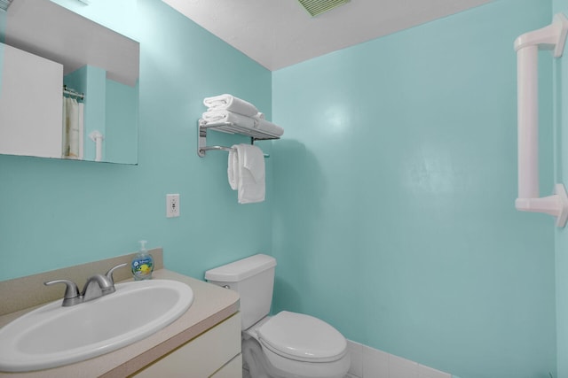 bathroom featuring visible vents, toilet, and vanity