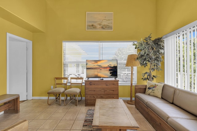 living room with light tile patterned floors, baseboards, and a towering ceiling