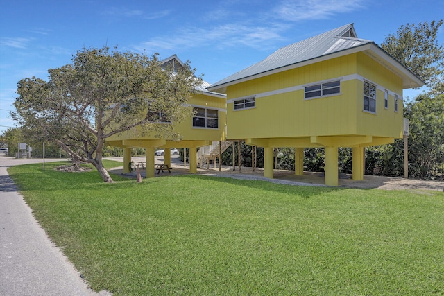 rear view of house with a lawn and stairs