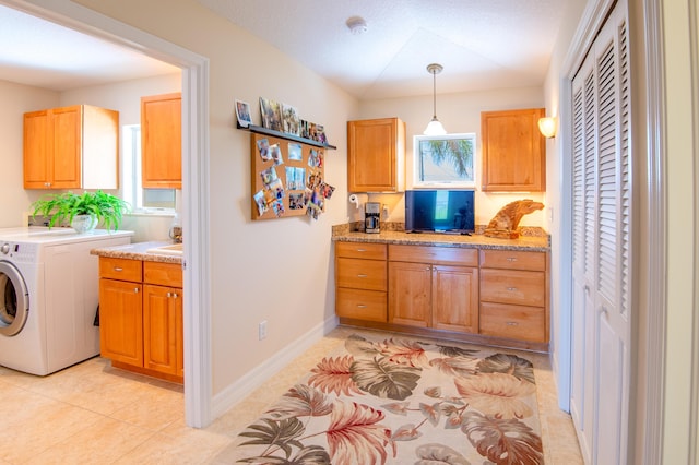 clothes washing area with washer / clothes dryer, light tile patterned floors, and cabinets