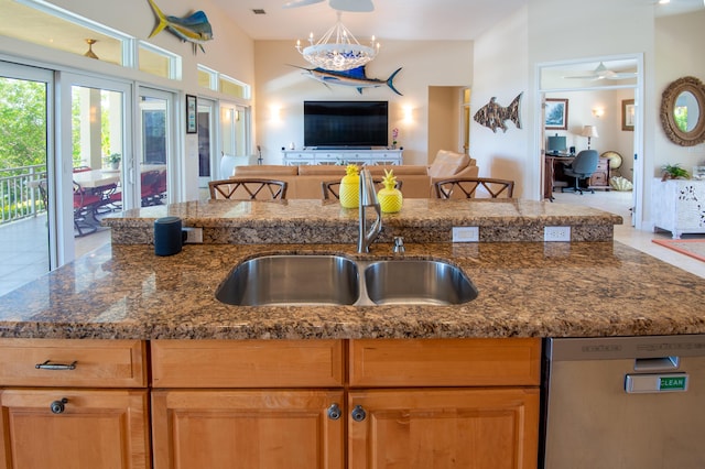 kitchen featuring dark stone countertops, sink, stainless steel dishwasher, and an inviting chandelier