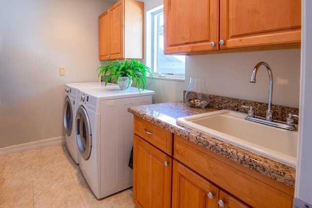 clothes washing area featuring cabinets, light tile patterned flooring, washer and dryer, and sink