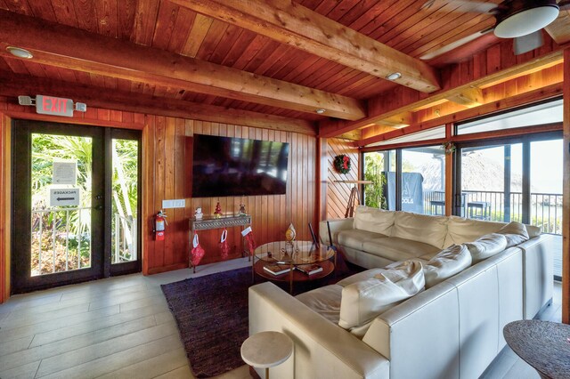 living room featuring beamed ceiling, wooden ceiling, light wood-type flooring, and wood walls